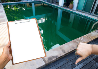 Clipboard in girl hand over green pool, Dirty pool water in tropical summer, swimming pool maintenance and service during summer season, pool water problem algae growing fast