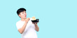 Close up tomboy Asian eating yummy hot and spicy instant noodle using chopsticks and bowl isolated on blue background in studio With copy space.