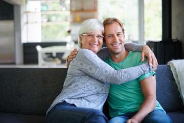 Wall Mural - I love having him offer. Portrait of a senior woman embracing her son while sitting on the sofa at home.