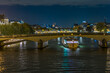 Historic Stone Bridge Over Seine River With Boat Cruise Skyline of Buildings in Paris at Night