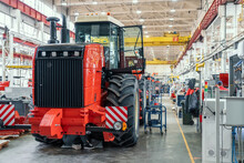 Big Red Harvester Or Tractor In Process Of Being Assembled On Production Line At Factory For Production Manufacturing Of Agricultural Machinery.