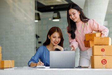 Portrait of Starting small businesses SME owners, two Asian woman check online orders Selling products working with boxs freelance work at home office, sme business online small medium enterprise