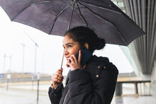 Smiling Ethnic Woman Speaking On Smartphone Under Umbrella On Street