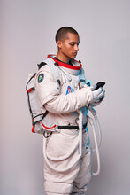 Serious Ethnic Astronaut Using Smartphone In Studio