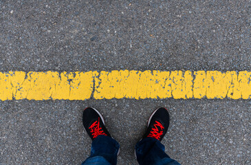 Top view of man feet behind yellow line