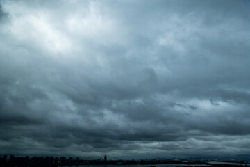 Wall Mural - dark clouds over a city by the sea