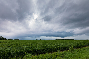 Thunderstorm with dark clouds moving across farm fields. Severe weather alert, dangerous storm and meteorology concept