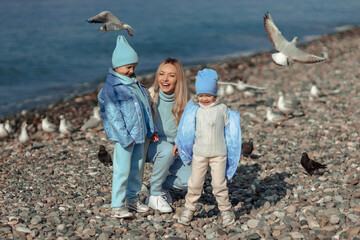 family vacation at sea in the off season. happy mother and children walking along the seashore