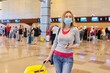 © Valerii Honcharuk - Woman passenger in medical protective mask at airport with luggage suitcase