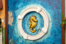 Artwork Of A Golden Sea Horse In A White Circle On The Wall Behind The Tables And Bar Stools Of A Cozy Bar In Willemstad, Curacao