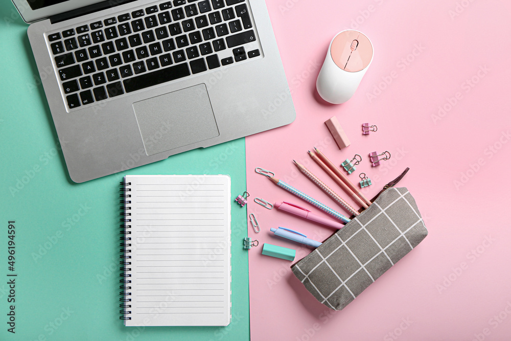 Blank notebook, laptop and stationery on color background