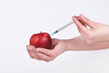 Wall Mural - apple fruit being injected with syringe. held by female hand.