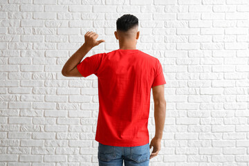 Wall Mural - Handsome young man in stylish t-shirt on white brick background, back view