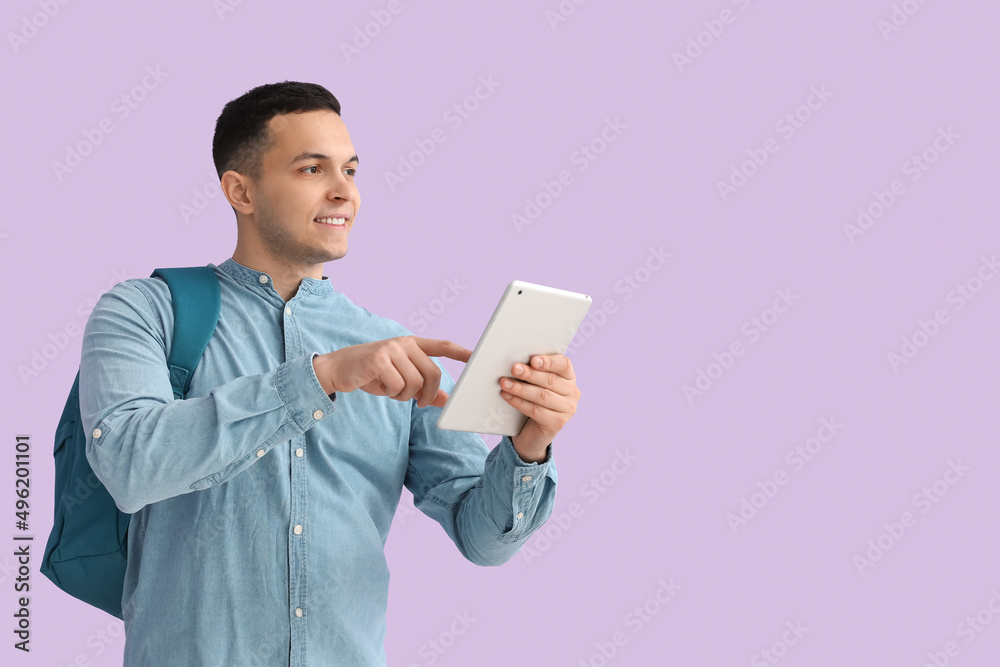 Male student using tablet computer on lilac background