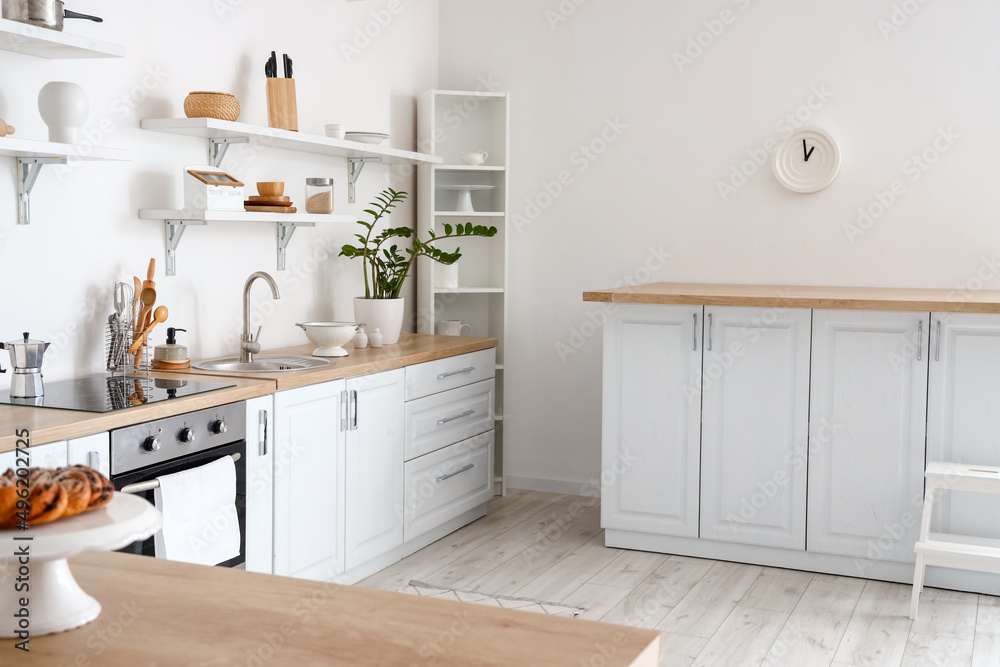 Counters with different utensils near white wall in kitchen interior