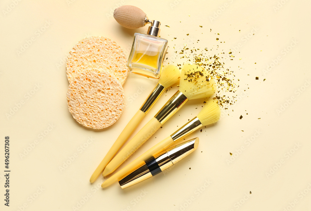Perfume, sponges and makeup brushes on light color background