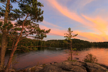 brilliant sunset over northern minnesota fishing lake fills sky with colorful clouds and subtle gold