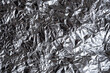 Abstract crumpled silver foil background. Shiny rumpled foil sheet texture.