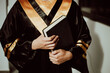 © artrolopzimages - Manos de persona graduada con diploma y libro en la mano. Concepto de graduación.