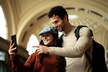 Beautiful couple at railway station waiting for the train. Young woman and man waiting to board a train.