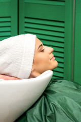 Wall Mural - Hairdresser wraps hair of a young caucasian woman in a white towel after washing head in the hairdressing salon