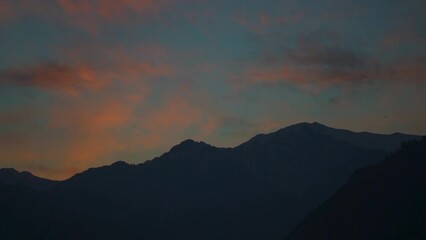 Wall Mural - Orange clouds above the snow covered Himalayan mountains during sunset at Manali in Himachal Pradesh, India. Sunset at the mountains. Nature background. Sky becomes orange above the mountains. 