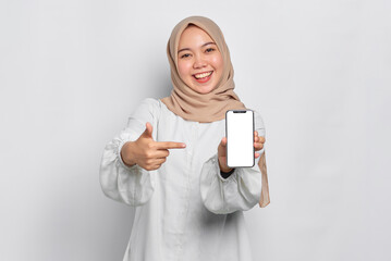 Wall Mural - Smiling young Asian Muslim woman showing mobile phone blank screen recommending App isolated over white background