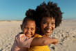 Side view of portrait of smiling african american mother and daughter enjoying sunny day at beach