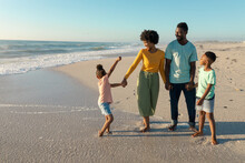 Happy African American Family Enjoying Sunny Day At Beach Against Blue Sky