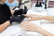 © splitov27 - Manicure master removes cuticles with electric file machine on female hand in nail salon