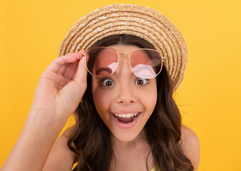 Canvas Print - surprised child in summer straw hat and glasses has curly hair on yellow background, beach fashion