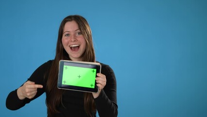 Portrait of woman posing hold tablet pc computer with blank empty screen green screen with tracking points isolated on blue background with mock up copy space