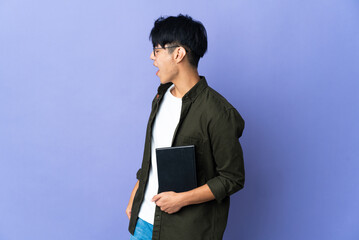 Wall Mural - Young student woman isolated on purple background laughing in lateral position