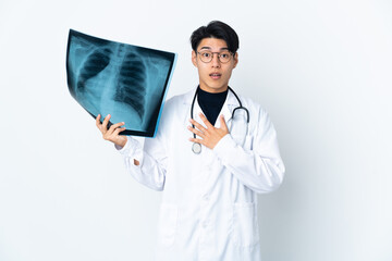 Young Chinese doctor man holding radiography isolated on white background surprised and shocked while looking right