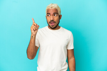 Wall Mural - Young Colombian handsome man isolated on blue background intending to realizes the solution while lifting a finger up