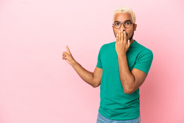 Wall Mural - Young Colombian handsome man isolated on pink background with surprise expression while pointing side