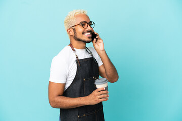 Poster - Restaurant Colombian waiter man isolated on blue background holding coffee to take away and a mobile