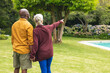 © WavebreakMediaMicro - Multiracial senior couple looking at view while standing in backyard