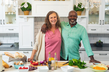 Wall Mural - Portrait of smiling caucasian senior woman and african american man cooking food at home