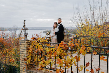 Wall Mural - Young cheerful wedding couple. A bride with a veil, a charming groom in a black suit.