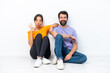 © luismolinero - Young caucasian couple sitting on the floor isolated on white background showing an ok sign with fingers