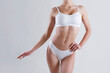 © Evrymmnt - Close up shot of unrecognizable fit woman in lingerie isolated on white background. Torso of slim attractive female with flat belly in white underwear. Copy space for text.