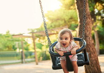 Wall Mural - I love this swing. Shot of little girl playing on a swing in a park.