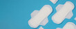 Woman sanitary napkins on blue background. Top view. Absorbent pads worn by women to absorb menstrual blood. Comfortable white sanitary napkins arranged on light blue paper. Represent Hygiene concept