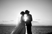 Foto In Bianco E Nero Di Una Coppia Di Sposi Che Si Abbracciano In Silhouette Al Tramonto