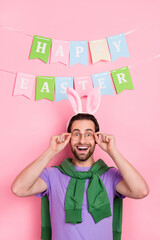 Poster - Photo of impressed good mood man celebrate easter holiday wear funny headband isolated on pink color background