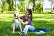 © Srdjan - Young beautiful woman in the park with her pet dog white Labrador Retriever that she adopt from the pet shelter to give him good life and love. Female animal lover with her adopted puppy having fun.