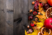 Autumn Background Maple Leaves, Apples, Rose Hips, Nuts, Chestnuts, Dried Oranges On A Wooden Table