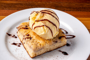 Ice cream with banana cake on a white plate on a wooden table. Delicious dessert.