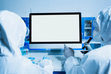 back view of scientist pointing at monitor with white screen near colleague in lab.